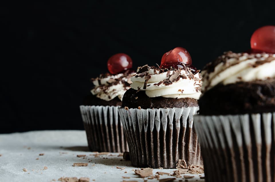 chocolate cupcakes with buttercream frosting and cherries on top