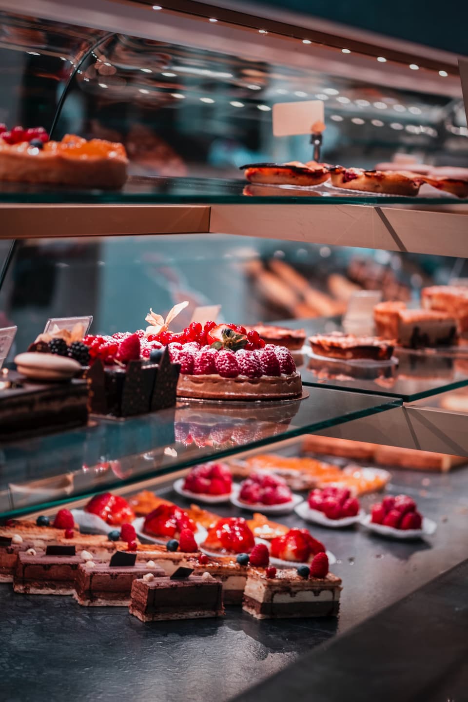 strawberry decorated chocolate cakes in a glass case