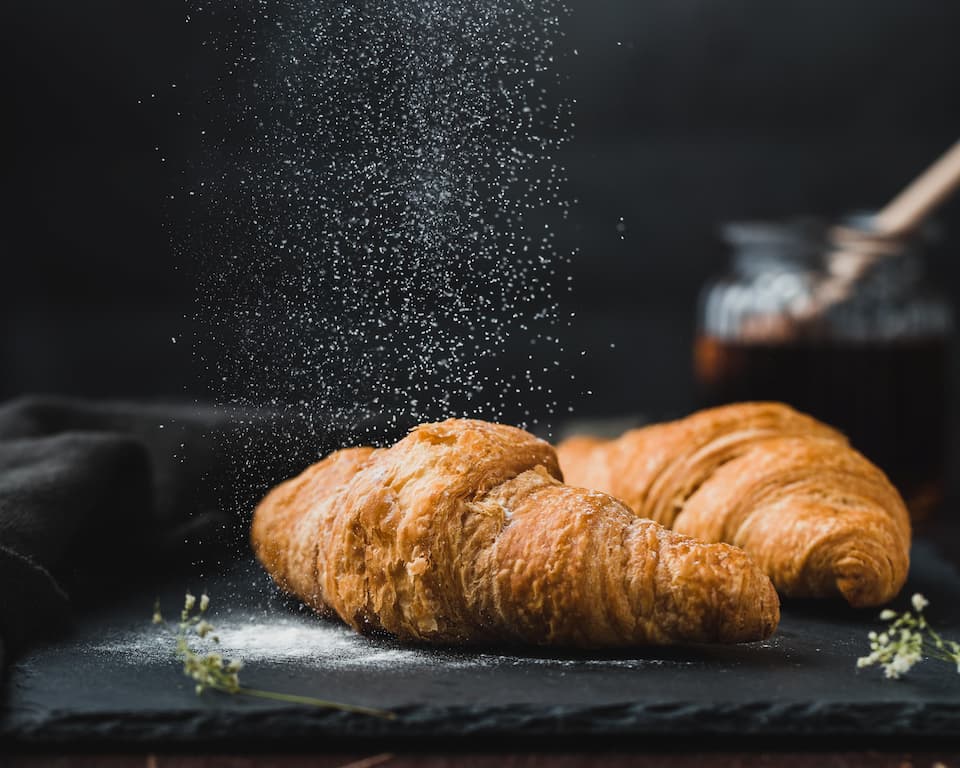 plain croissant with salt being sprinkled over it